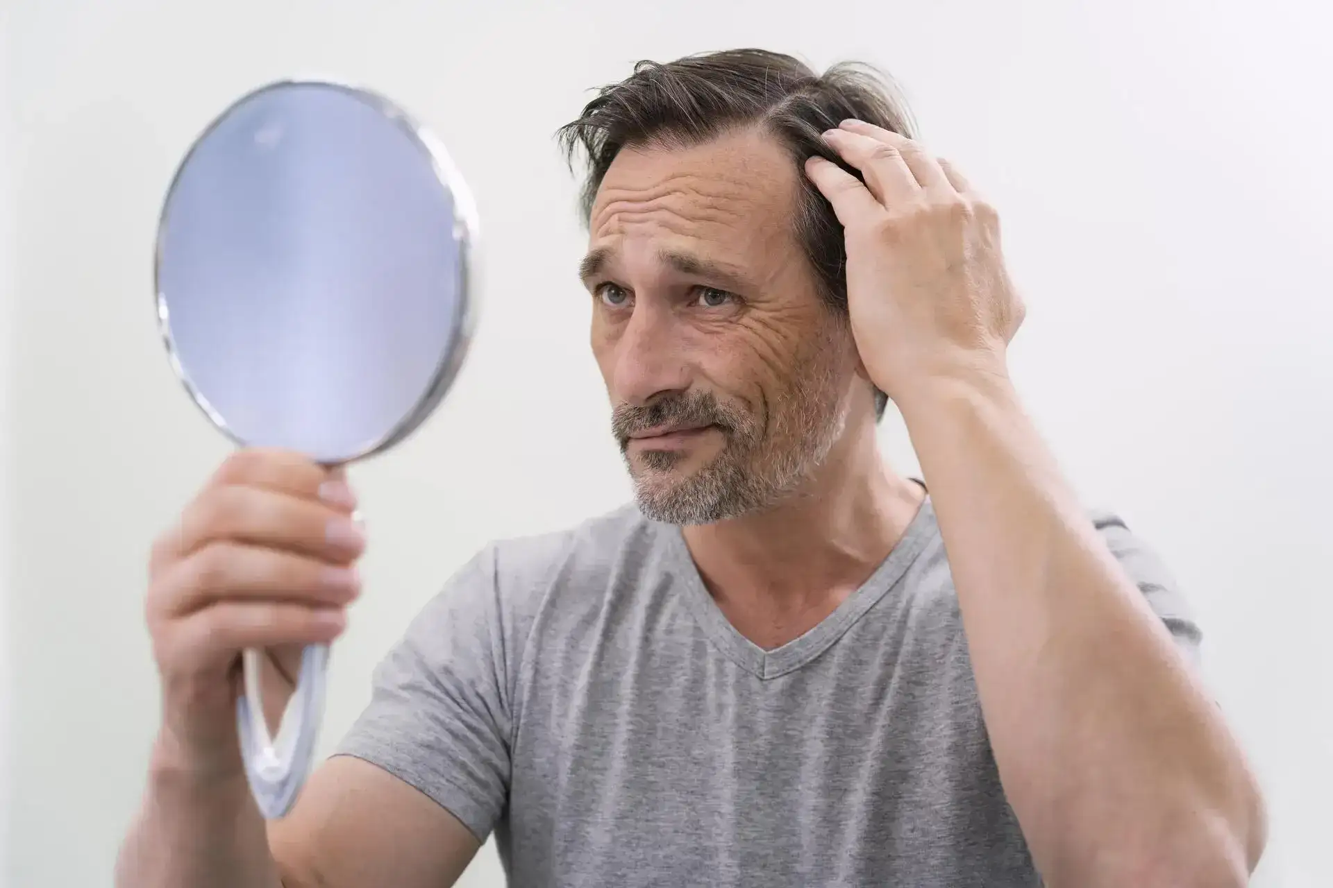Middle-aged man checking hair growth progress after hair loss treatment at Elegance Cosmetic Clinic