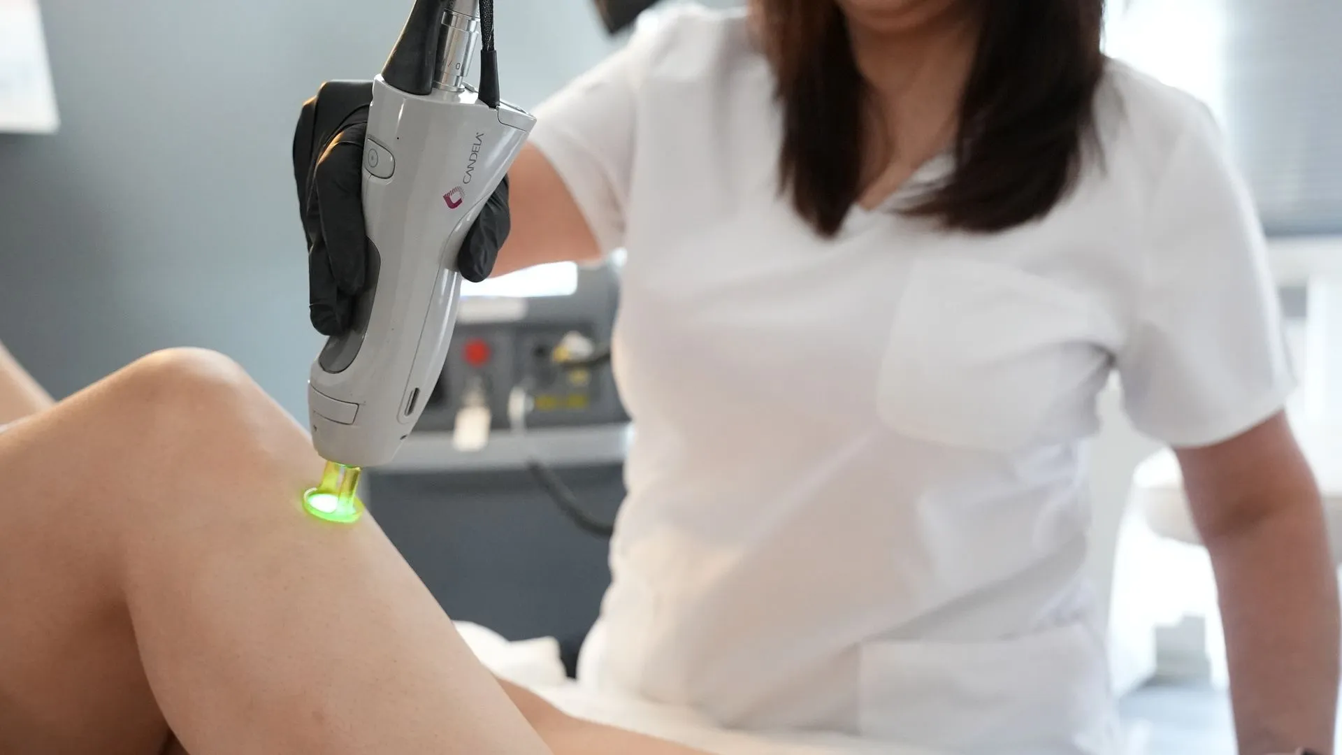A clinician holds a Candela GentleMax Pro handpiece against a patient’s leg, delivering precise laser hair removal treatment.