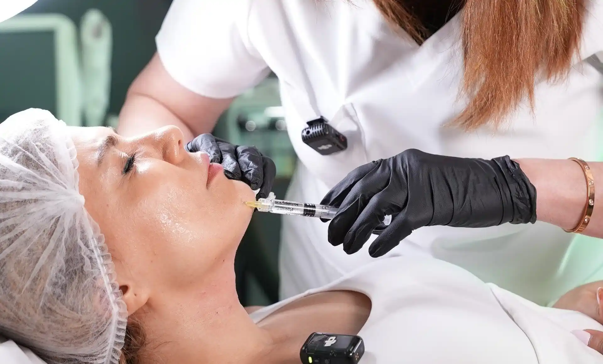 Clinician wearing black gloves carefully injecting dermal filler into a patient’s jawline under sterile conditions.